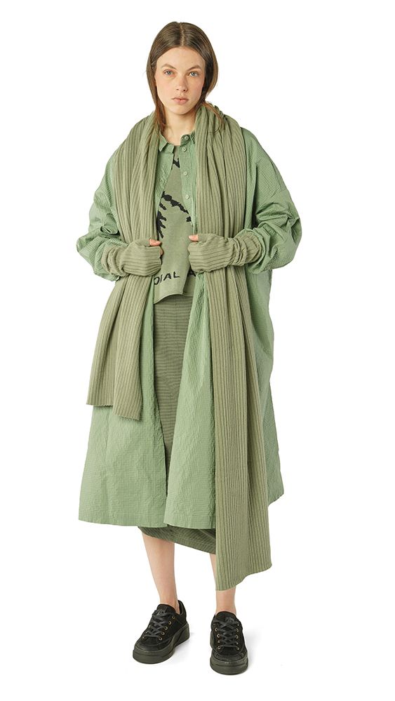 Frau trägt oversized mintgrünen Strickmantel mit weitem Schnitt und schwarze Sneakers.