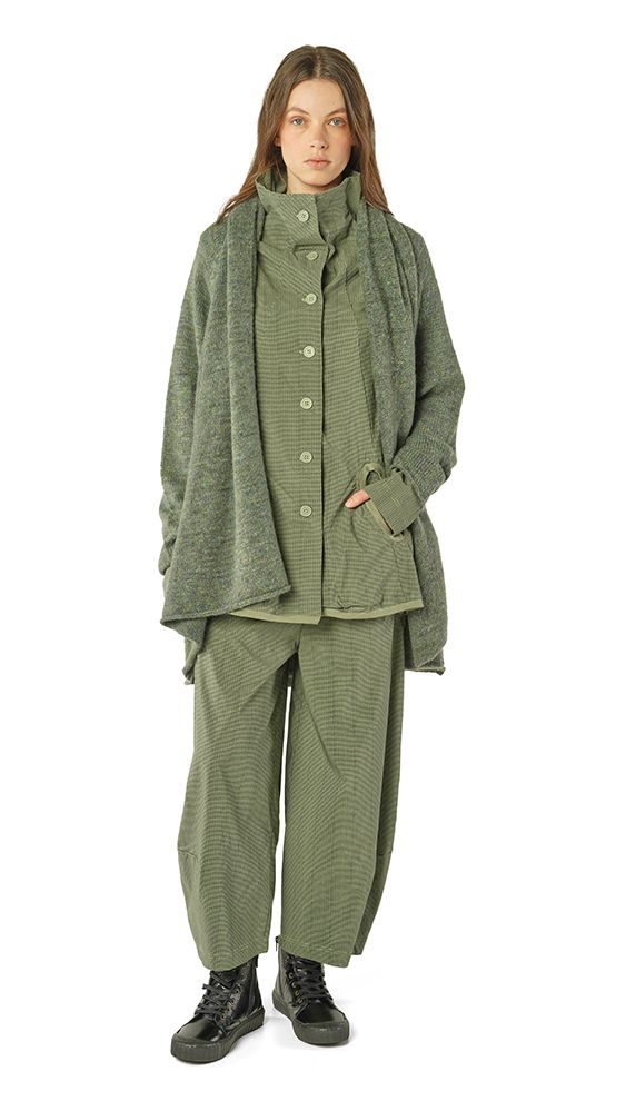 Frau trägt oversized olivgrünen Strickmantel mit weitem Schnitt und passende Hosen, schwarze Stiefel.
