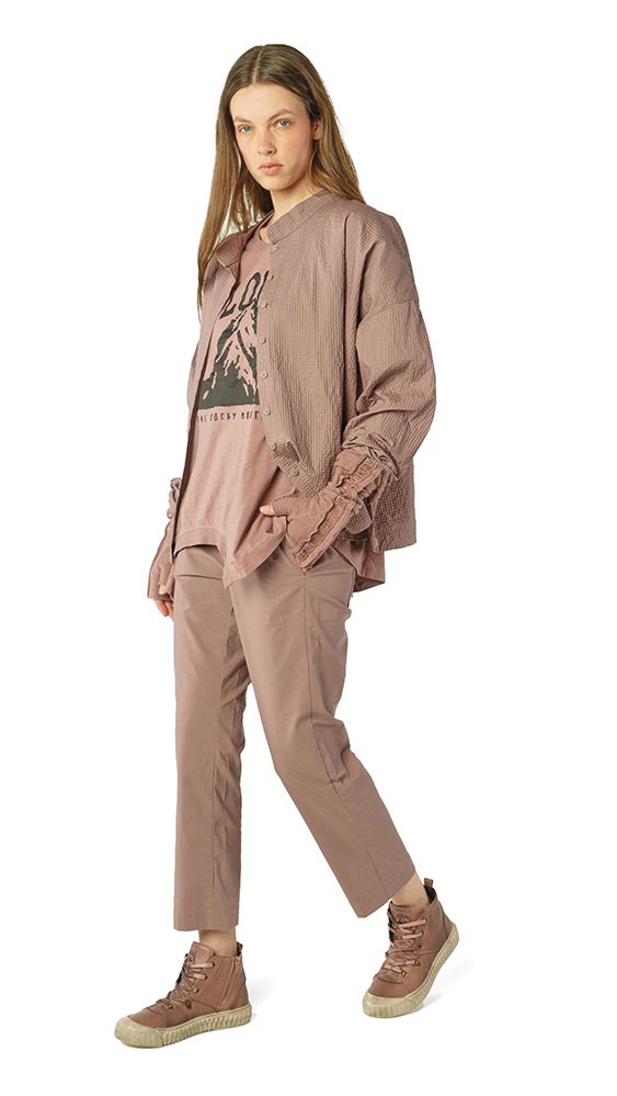 Frau trägt oversized beige Sweatshirt mit Aufdruck, weite beige Jogginghose und braune Sneaker.