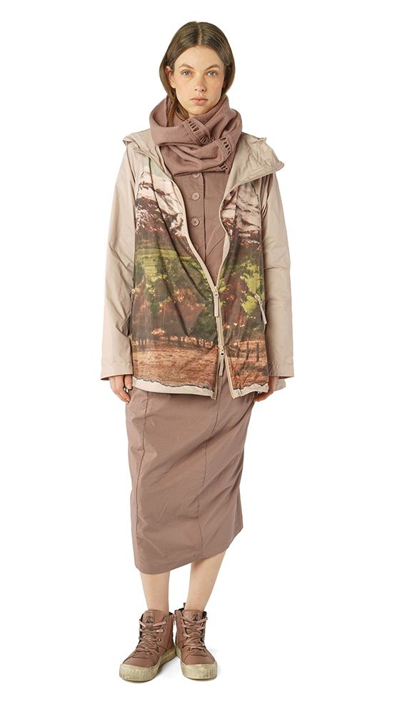 Frau trägt oversized Jacke mit Muster, langer Rock und robuste Stiefel, beige Schal um den Hals.
