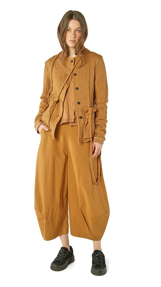 Frau trägt oversized beige Jacke mit Weste, weiten Hosen und schwarzen Sneakern.
