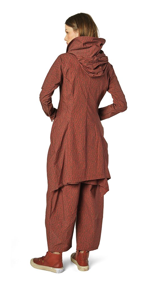 Frau trägt oversized rustfarbenen Strickmantel mit weitem Schnitt und passende weite Hose, rote Sneakers.