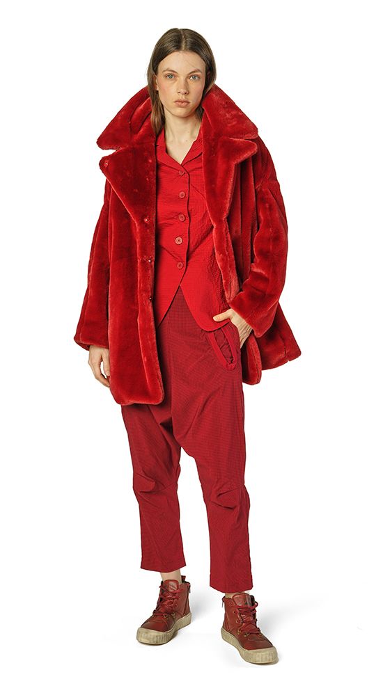 Frau trägt roten Veloursanzug mit oversized Jacke und robusten Stiefeln.