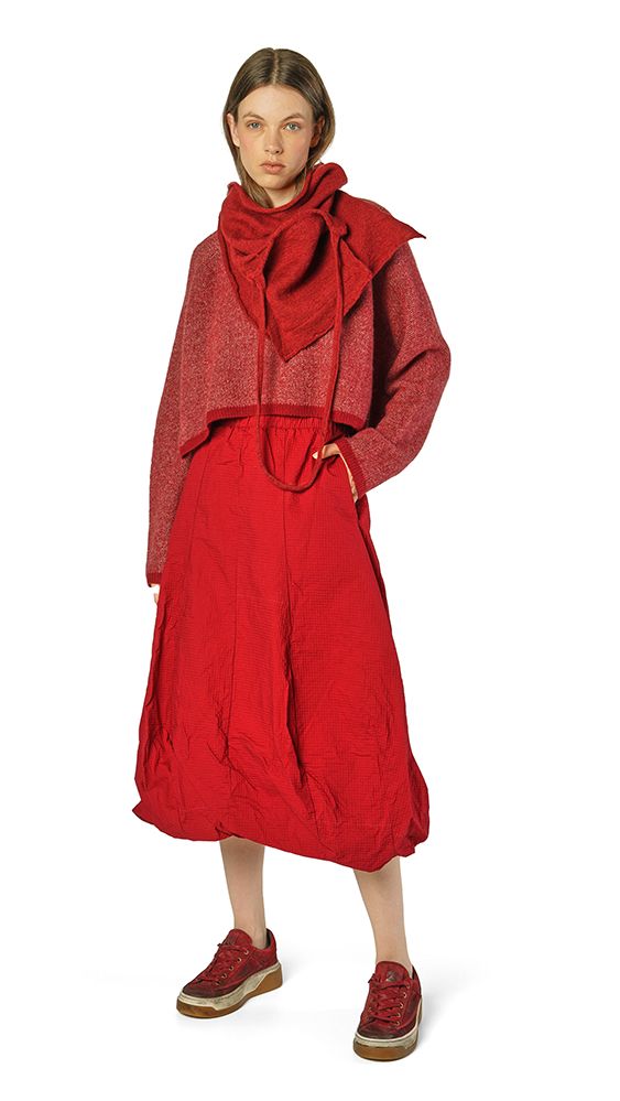 Frau trägt oversized roten Wollmantel mit Schal und rote Hose, kombiniert mit roten Sneakern.