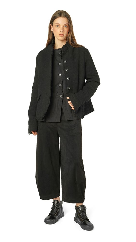 Frau trägt oversized schwarzen Blazer, schwarzes Top und weite schwarze Hosen mit robusten Stiefeln.