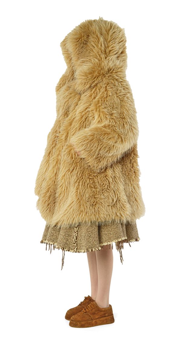 Langer, flauschiger, beige Farbfellmantel mit Fransenunterteil und braunen Schuhen.