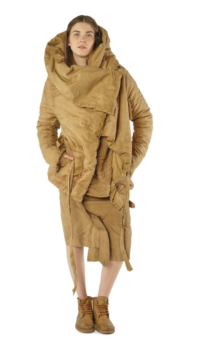 Person trägt oversized, beige-farbene, pelzbesetzte Robe mit weitem Schnitt und robusten Stiefeln.