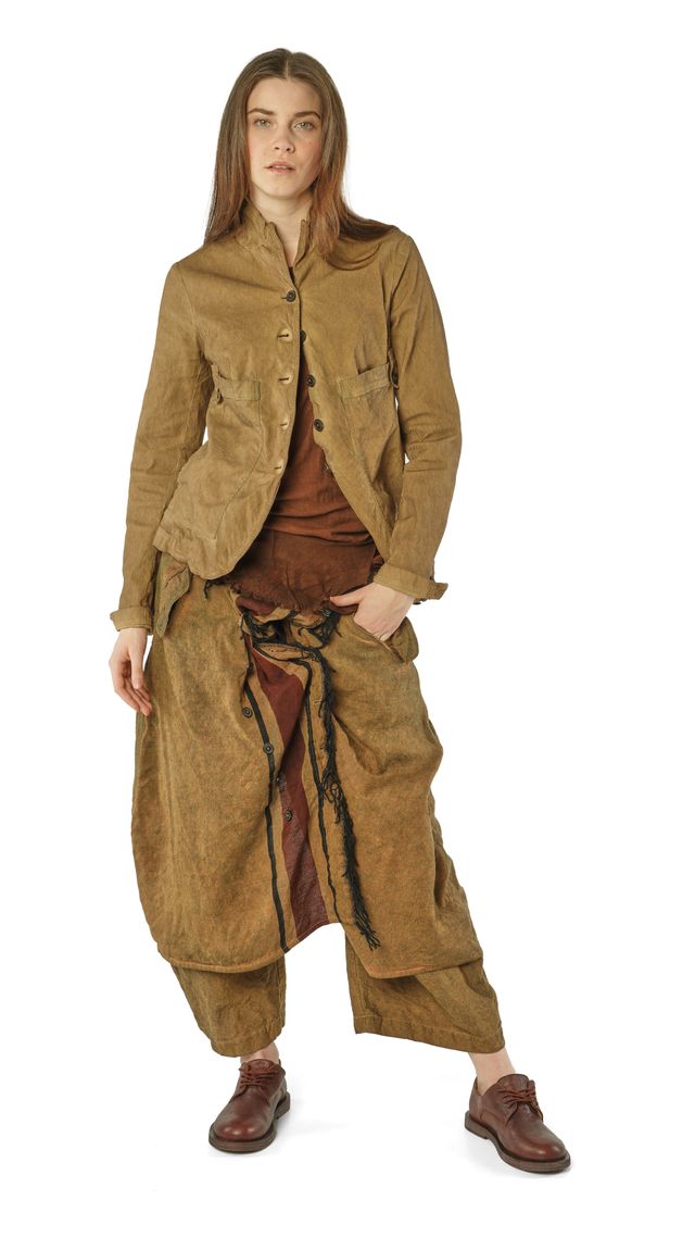 Person trägt oversized, beige-farbene Patchwork-Jacke mit weitem Rock und braunen Stiefeln.