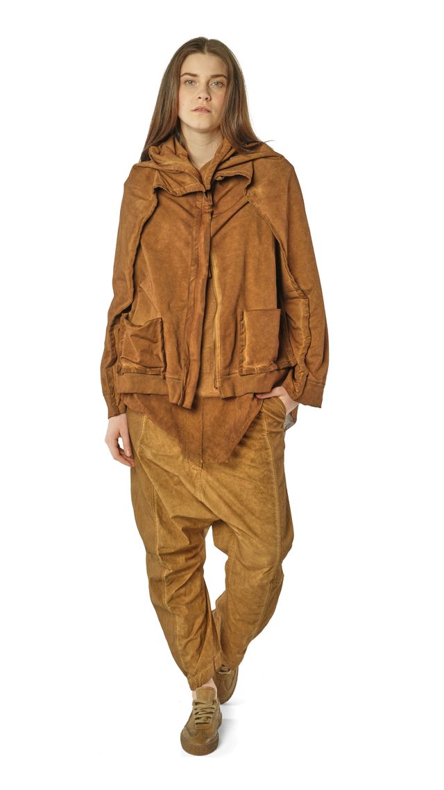 Person trägt beigefarbenen oversize Lederlook-Jackenanzug mit weitem Schnitt und flachen Schuhen.