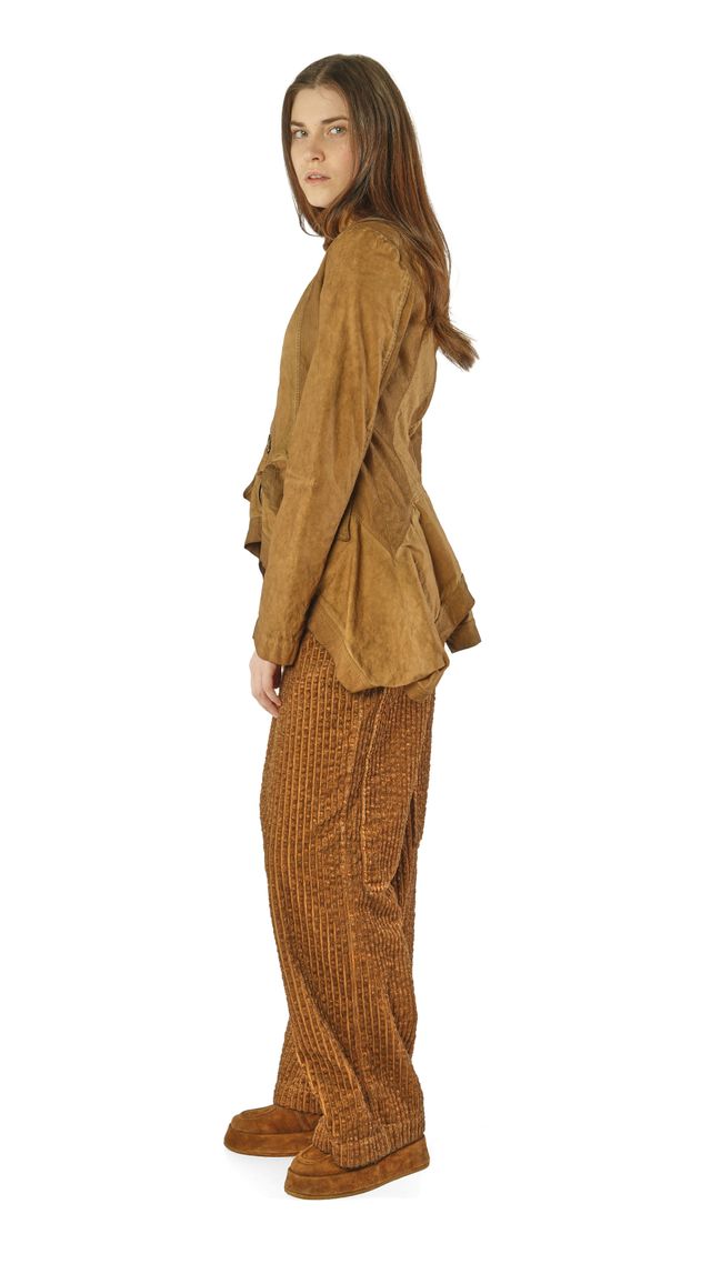 Person trägt beige oversize Bluse mit weitem Rock und passenden Hosen, steht seitlich.