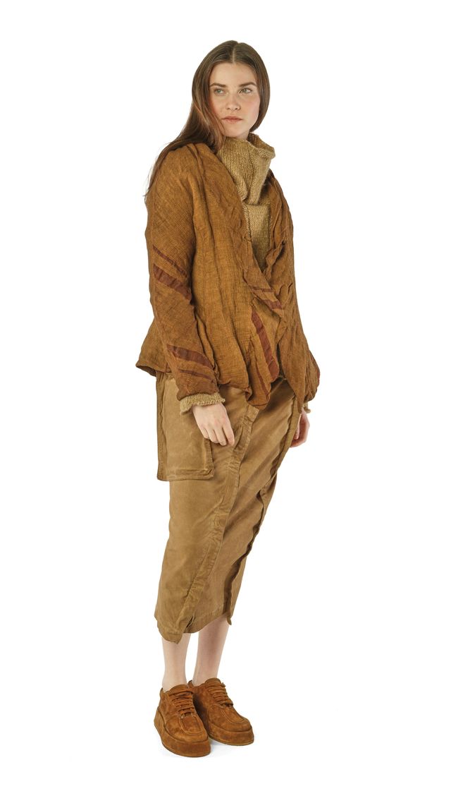Frau trägt warme, beige-braune Strickjacke, weite Hosen und Stiefel, natürlicher Look.