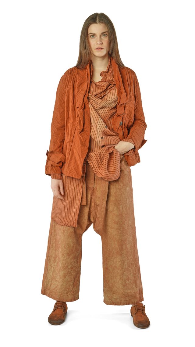 Frau trägt rustikale, oversized Brauntöne-Kombi mit Schal und weitem Jackett, bequeme Stiefel.