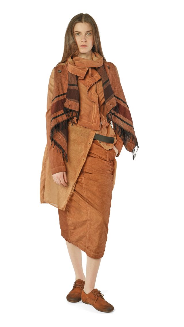 Frau trägt rustikalen, langen braunen Mantel mit Fransen über beigeem Wickelkleid, beige Schal und braunen Stiefeletten.