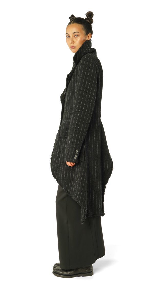Frau trägt eleganten, oversized schwarzen Strickmantel mit asymmetrischen Säumen und schwarzen Pants.