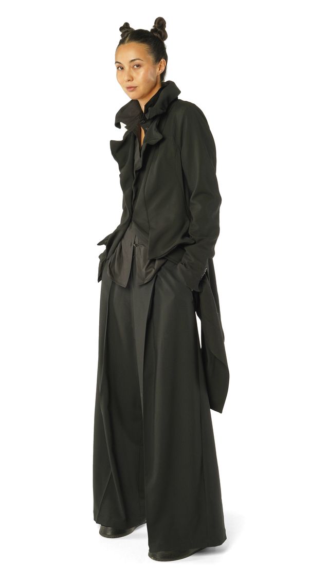 Frau trägt eleganten, langen schwarzen Mantel mit Kapuze, schlicht und modern.