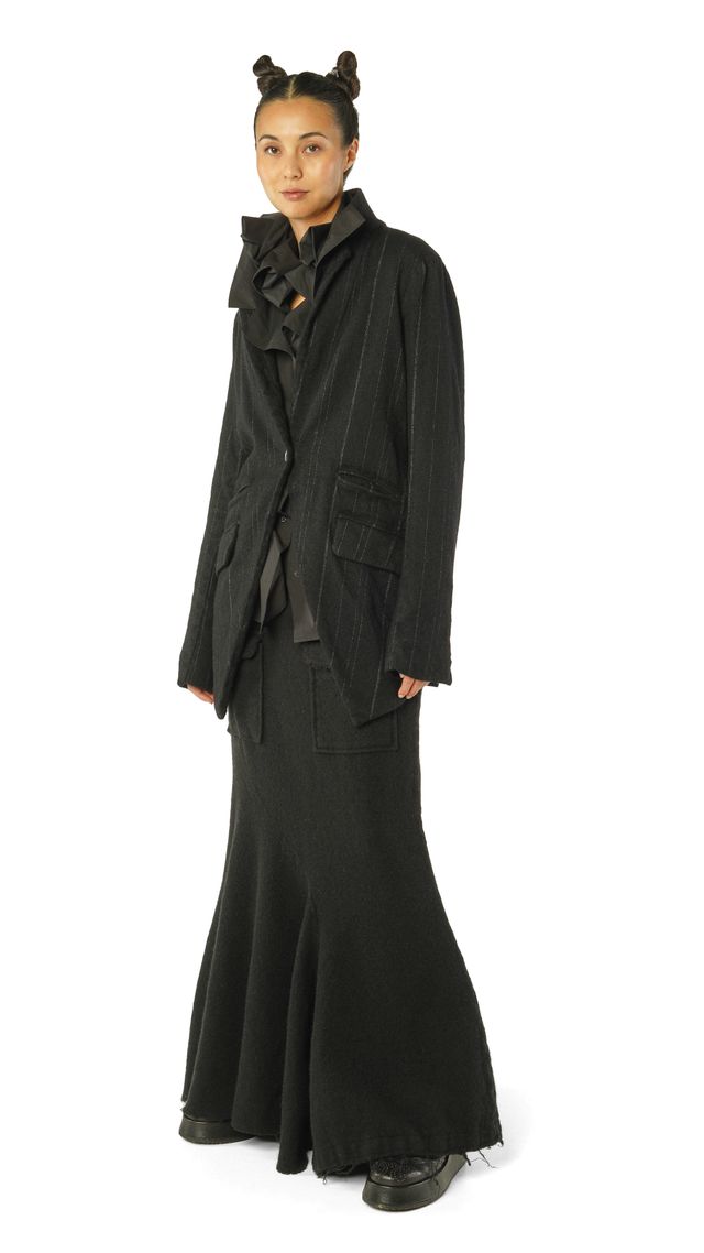 Frau trägt elegantes, langes schwarzes Kleid mit Cape und Accessoires, stilvoll mit Buns.