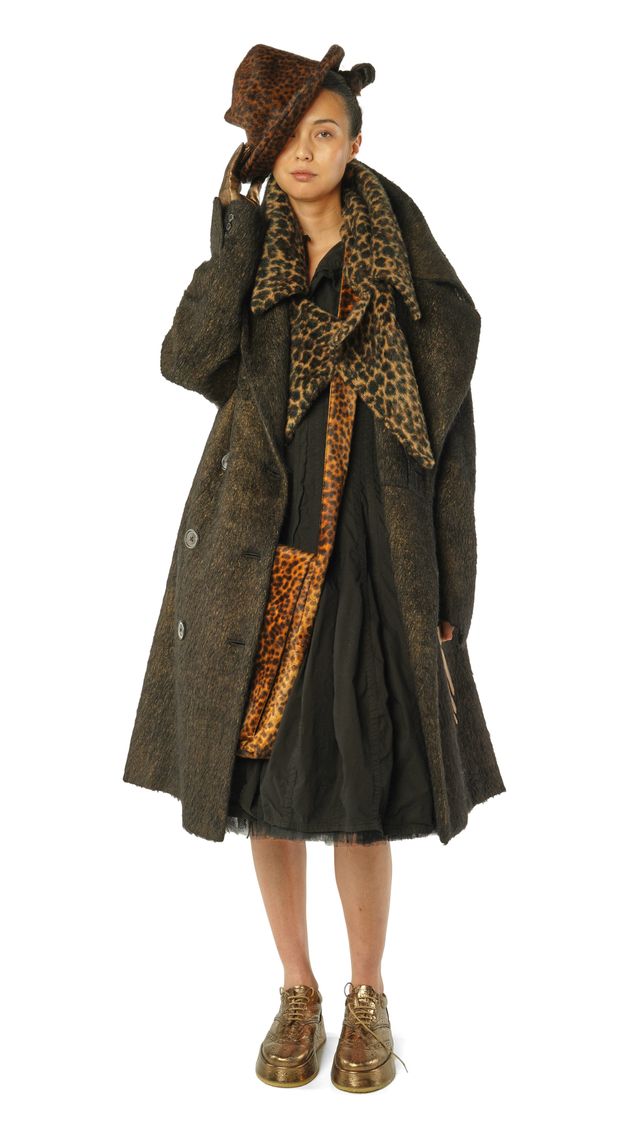 Frau trägt langen, gemusterten Mantel mit Leoparden-Schal und Hut, goldene Stiefeletten.