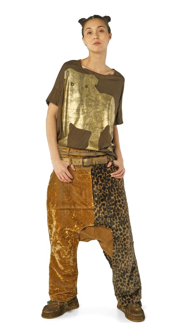 Person trägt bunte, gemusterte Upcycling-Kleidung mit Tierprint-Hose und gold-schimmerndem Top.