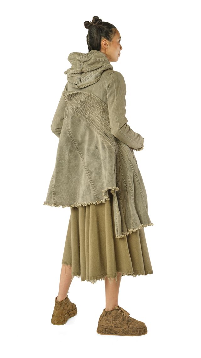 Frau trägt langes, fransenbesetztes Kleid mit Hood und bequemen Schuhen, elegant und lässig.