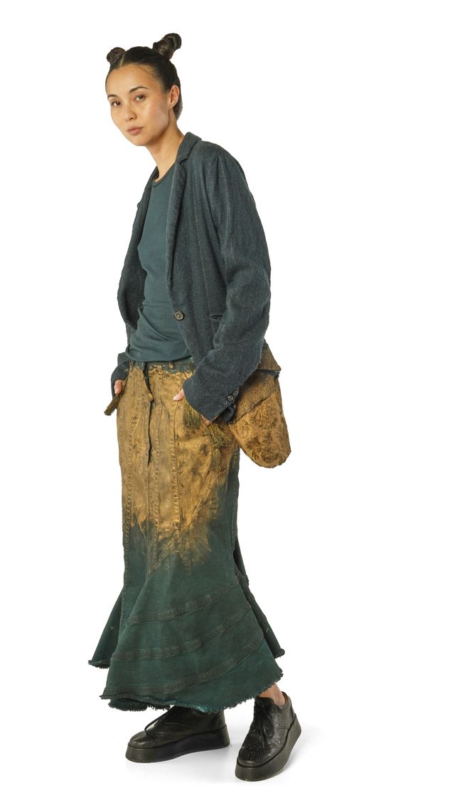 Person trägt oversized Jacke, lange Wickelrobe und bequeme Schuhe, Haar zu zwei Bünden gebunden.