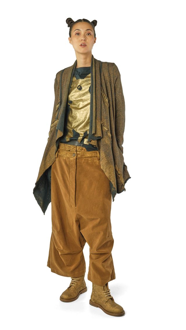 Person trägt bunte, oversized Kleidung mit Musterjacke, goldener Bluse und weiten Beinen, kombiniert mit robusten Stiefeln.