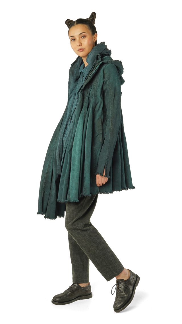 Person trägt grünen, weiten Wollmantel mit Ohren-Accessoire, schwarze Hose und Schuhe.