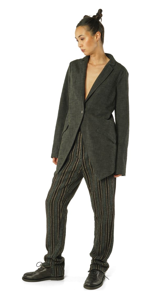 Frau trägt schicken oversized Blazer mit weitem Rock, gestreiften Pantalons und schwarzen Stiefeln.