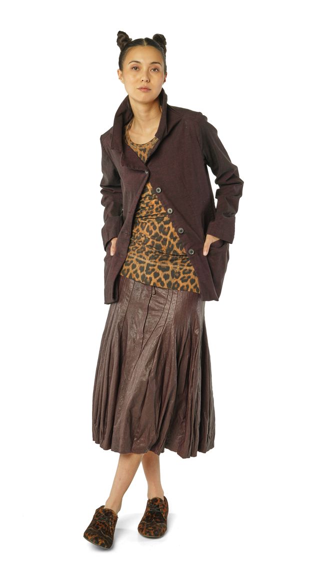 Frau trägt langen braunen Mantel mit leopardbedrucktem Kleid und Accessoires, bunte Haarbänder.